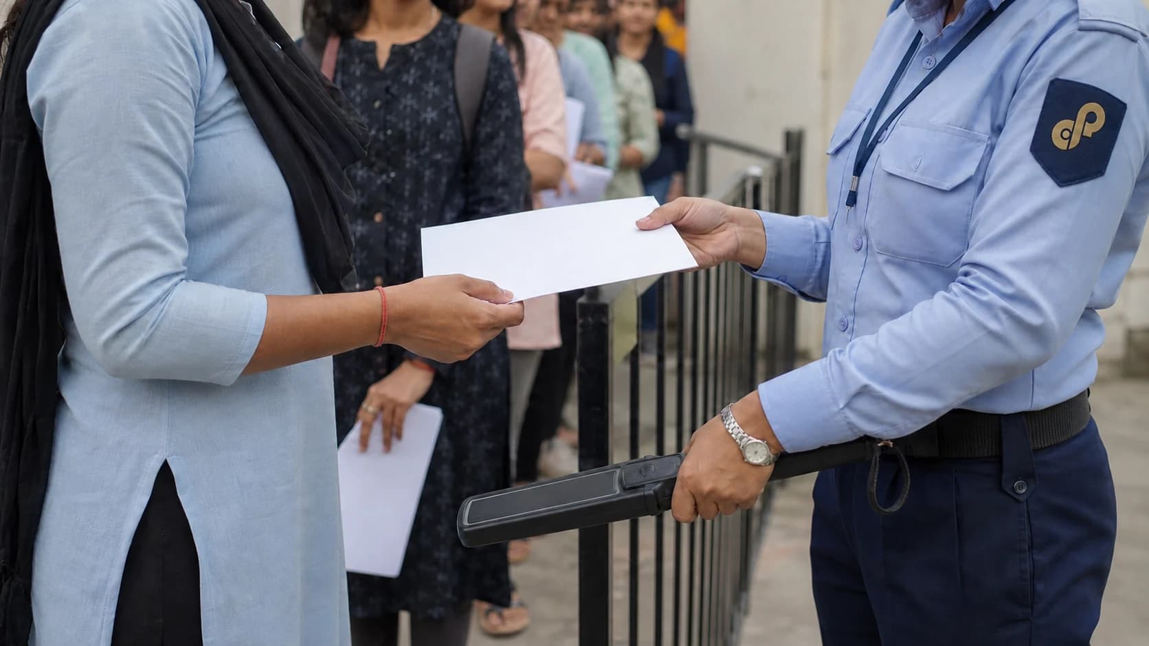 Woman CISS security officer checking a candidate’s document at an examination entrance.