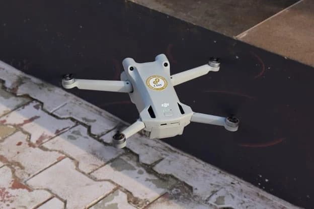 A CISS-branded drone hovering above a paved path, seen from above.