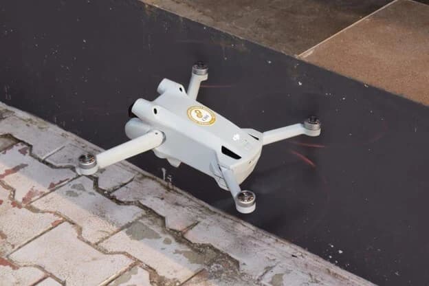 A CISS-branded quadcopter drone in flight just above a paved walkway.