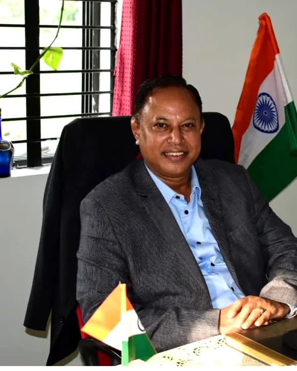 Cdr. Satyajit Roy (Retd.) at his desk, with the national flag behind him
